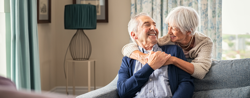 Life Assure Seniors Couple Enjoying Time Together In Living Room Hero